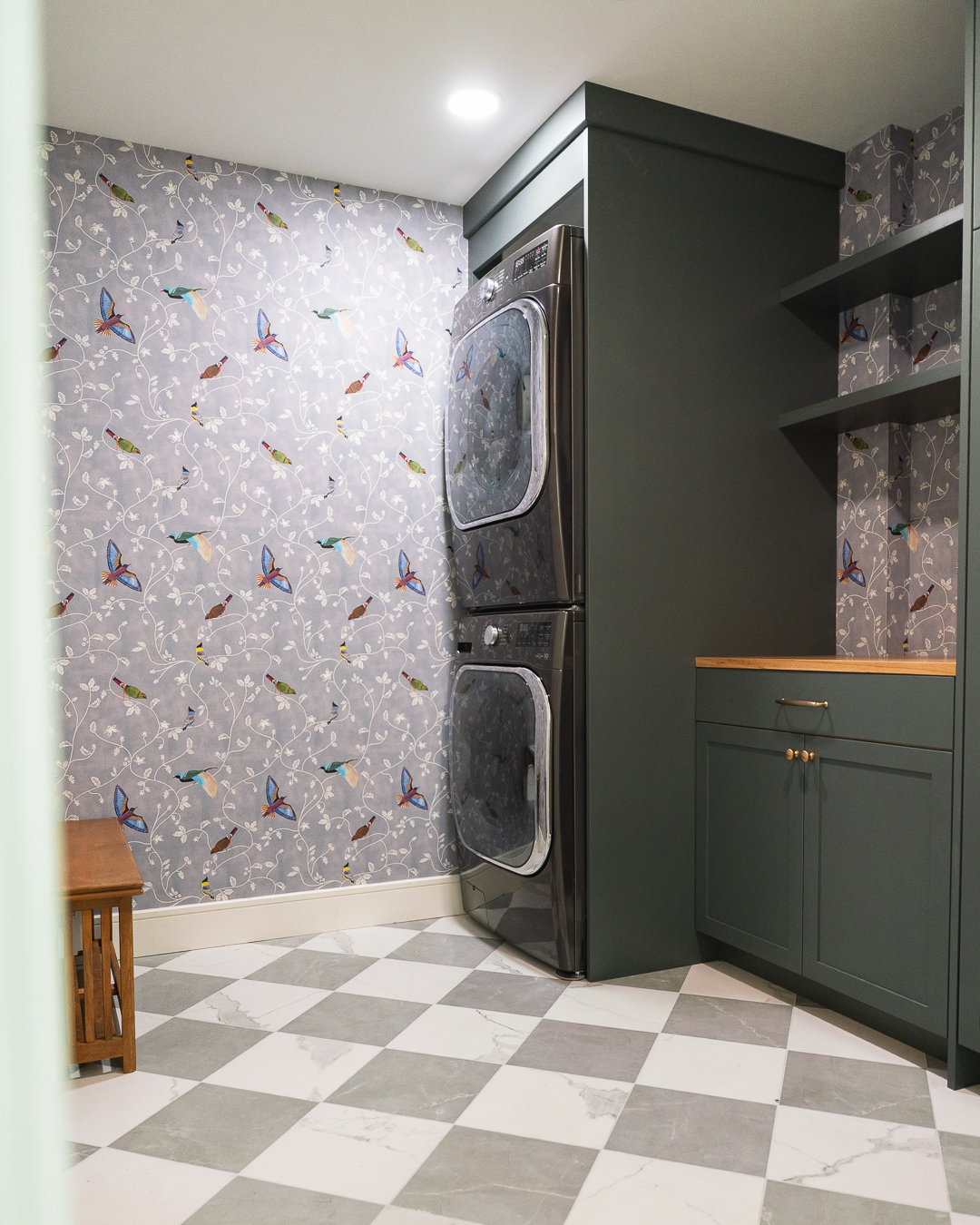 A renovated laundry room with patterned wallpaper and checkboard tile floor